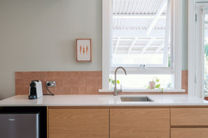 Modern kitchen with white countertop, wooden cabinets, and a window.