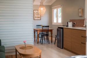 Kitchen and dining area with wooden table and chairs, refrigerator, and window.